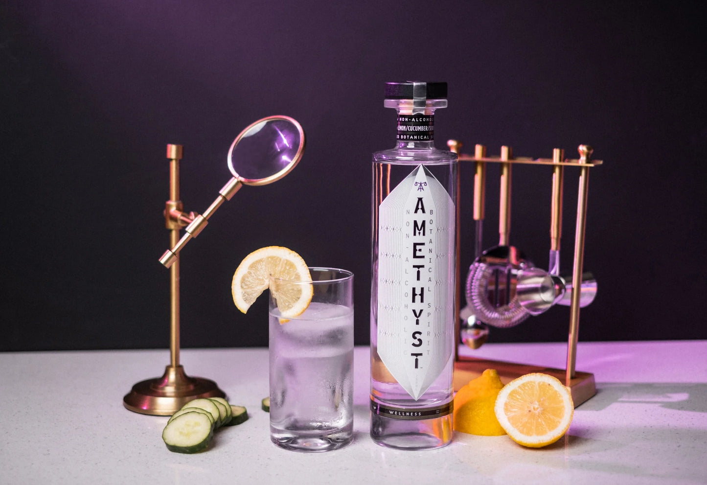 Amethyst botanicals non alcoholic spirit lifestyle pictured with a glass tumbler garnished with lemon slice. Barware in the background. Made for mocktails, non alcoholic beverages, and the sober curious.